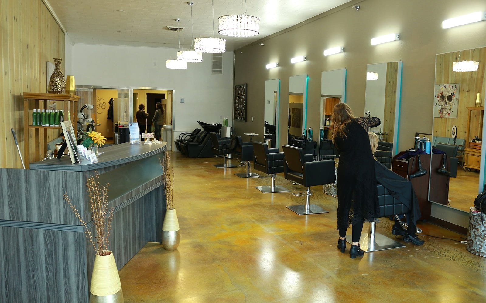 The G2 Hair Studio floor: reception desk, black styling chairs, crystal pendant lights and a stylist at work