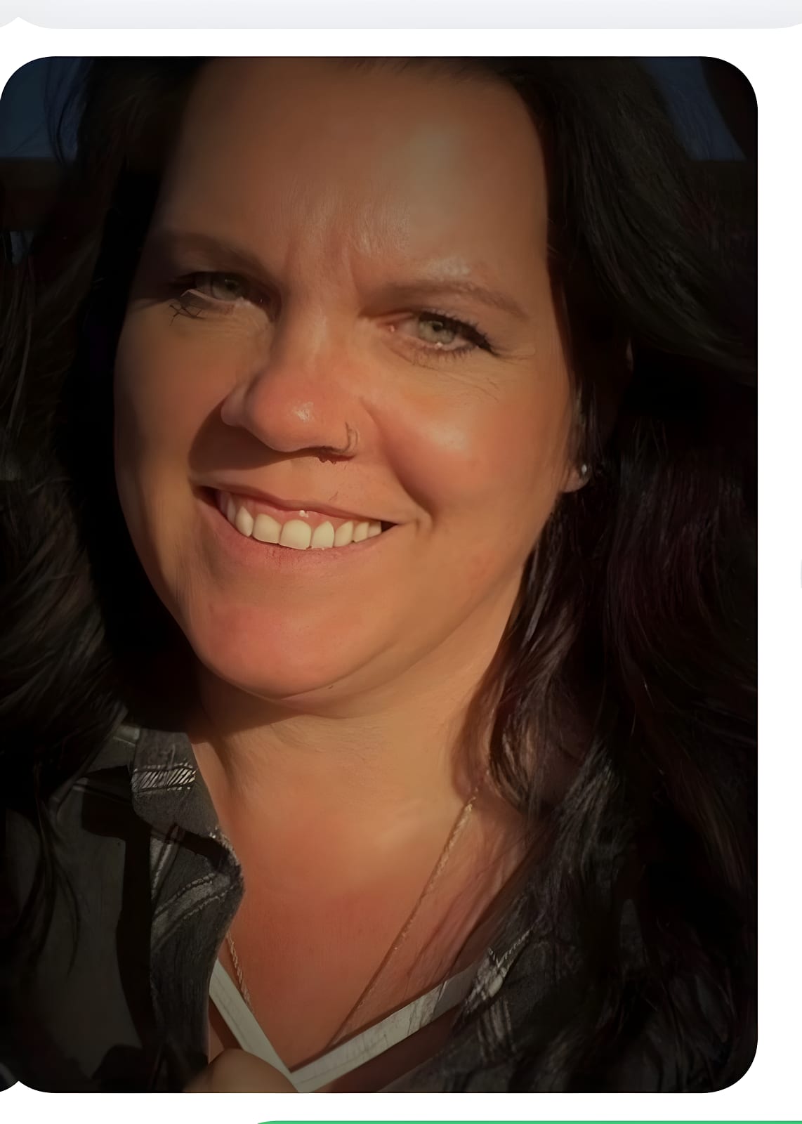 Smiling team member with dark hair in sunlight, wearing a plaid shirt